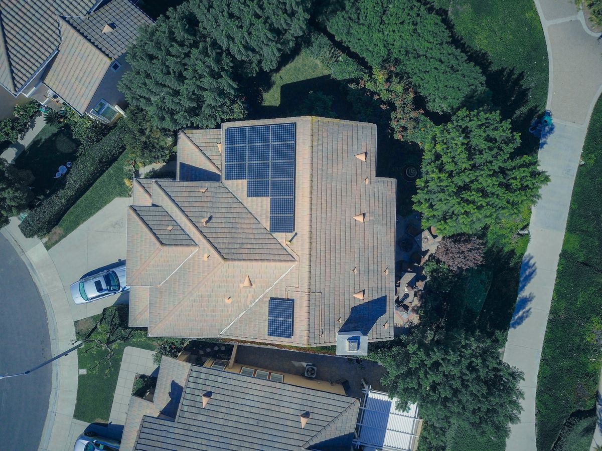 Aerial view of a suburban house with solar panels on the roof