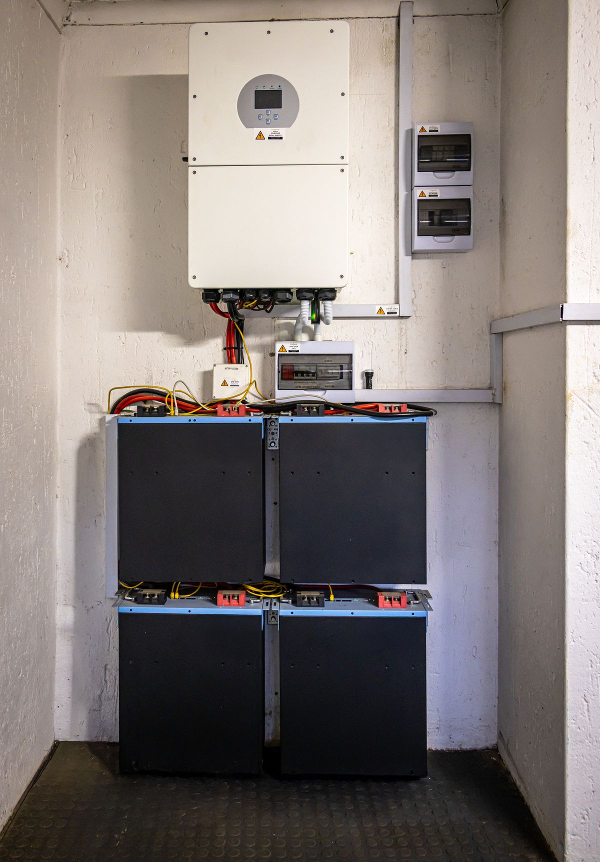 Wall-mounted home battery and inverter installed on a residential exterior wall