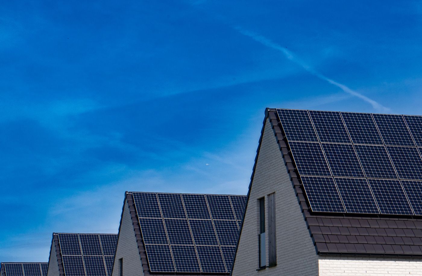 Modern home with a rooftop solar array against a clear blue sky