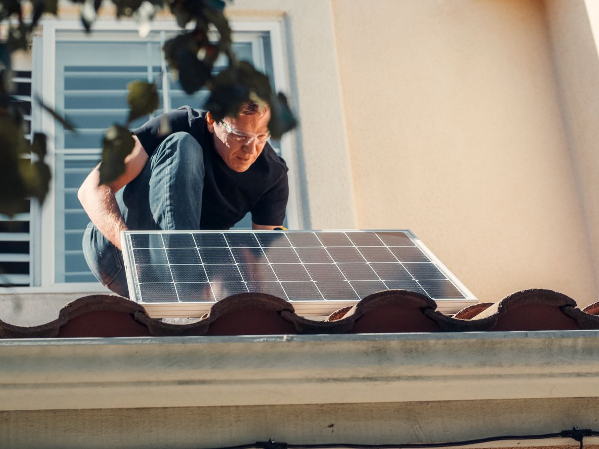 Solar technician placing a panel along a roof rail