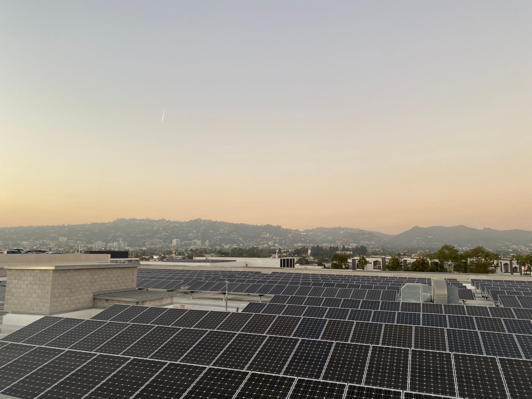 Rooftop solar array at sunset with hills on the horizon